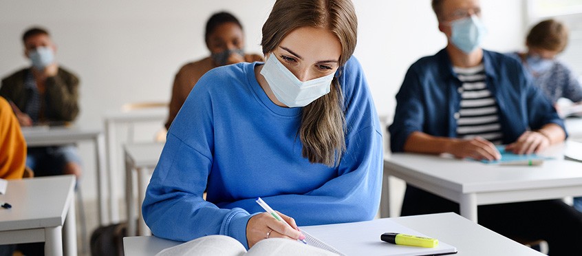 Mujer estudiando en la universidad con mascarilla